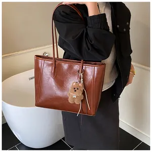 Sac fourre-tout vintage marron foncé avec charm ours porté par un mannequin en intérieur