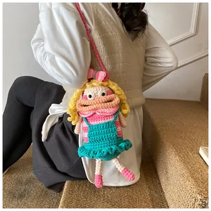 Close-up of handmade crochet doll bag with yellow hair and blue dress on a model