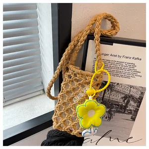 Close-up of khaki woven mini crossbody bag with yellow flower charm and thick rope strap