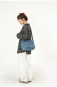 Model wearing a vintage light blue denim crossbody bag with multiple functional zip pockets