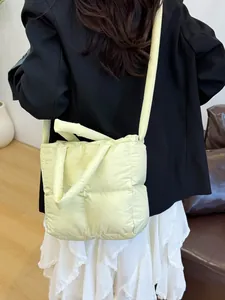 Quilted down cotton puffer tote bag in pale yellow being worn as a crossbody shoulder bag