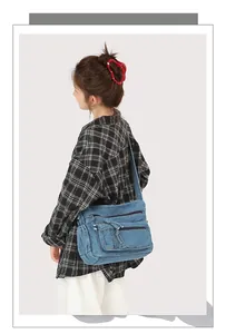 Blue denim crossbody bag detail showing multiple functional zipper pockets and straps