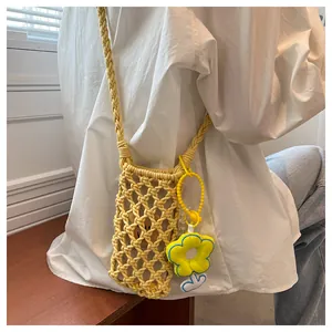 Detail of yellow hollow knit phone bag featuring a soft floral charm and braided strap