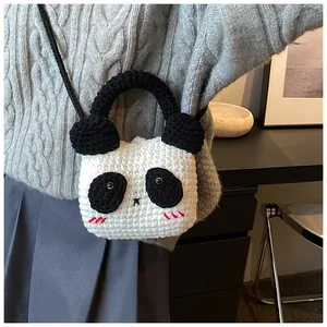 Detail of a handmade crochet panda bag worn over the shoulder with a black braided strap