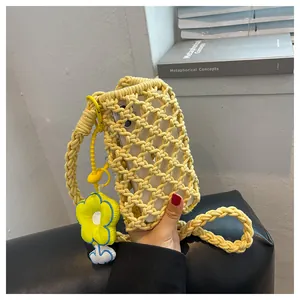 Detail of yellow woven phone bag with crochet flower charm and crossbody strap
