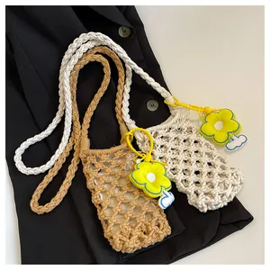 Detail of hollow woven mini crossbody bag with a decorative yellow flower pendant