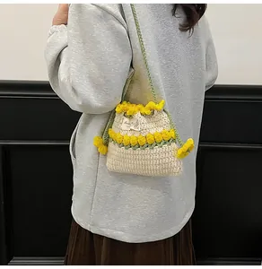 Detalle de bolso tipo saco tejido a mano con tulipanes amarillos y asa verde