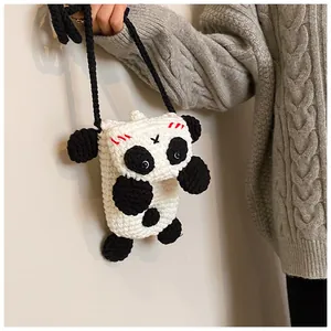 Detail of handmade crochet panda bag with thick yarn texture and red blush stitching