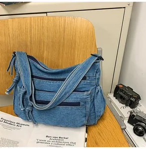 Detailed shot of retro denim messenger bag with triple front zippers on wooden seat