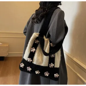 Détail d'un sac cabas en tricot avec fleurs 3D porté avec un manteau gris chic