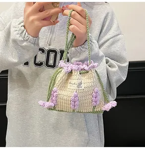 Detalle del bolso saco de ganchillo hecho a mano en blanco roto con flores púrpuras