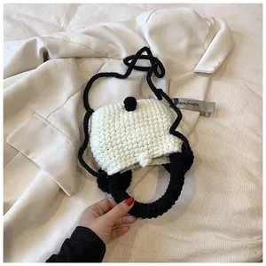 Close-up of handmade crochet bag showing textured white knit and black woven handle