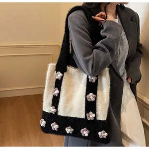 Détail du sac cabas en tricot avec blocs noirs et blancs et fleurs 3D sur l'épaule