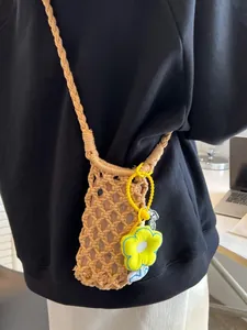 Mini woven hollow straw crossbody bag for beach vacation with yellow flower charm