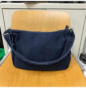 Close-up of vintage blue denim crossbody bag showing fabric texture and white stitching