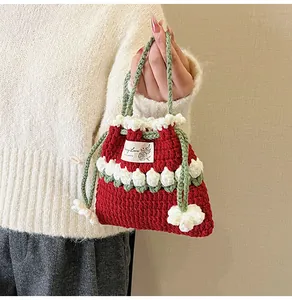 Detalle del bolso de ganchillo rojo hecho a mano con flores blancas y asas verdes
