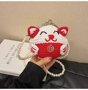 Dettaglio macro di borsa a uncinetto gatto della fortuna con cinturino di perle e ciondolo