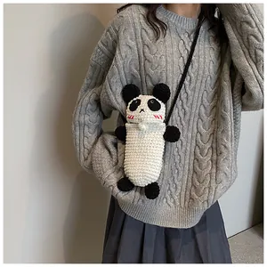 Close-up of a handmade crochet panda crossbody bag with 3D ears on a knit sweater