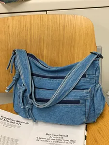 Vintage blue denim crossbody bag with multi-zipper pockets on a wooden chair