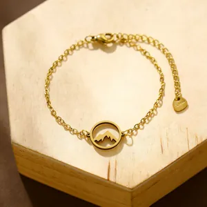 Minimalistisches goldenes Edelstahlarmband mit hohlem Berg-Anhänger auf einem Holzständer
