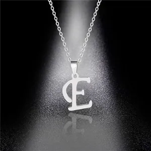 Detailed view of polished stainless steel silver letter E pendant necklace on dark surface