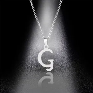 Macro shot of polished silver letter G pendant on a delicate chain necklace