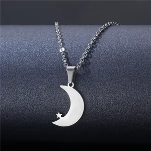 Minimalist silver moon and star pendant necklace on a dark textured display stand
