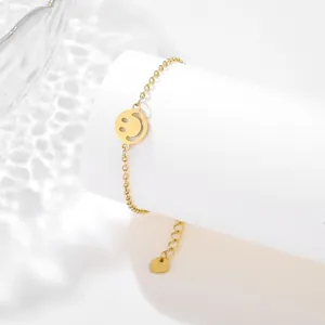 Detail of gold stainless steel bracelet with hollow smiley pendant on white pedestal