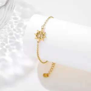 Detail view of gold anchor and ship wheel bracelet with polished stainless steel finish