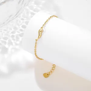 Macro shot of gold angel wing pendant and S925 heart charm on stainless steel chain