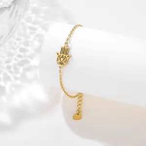Detail of a gold Hamsa Hand bracelet on a white pillar with water ripple lighting