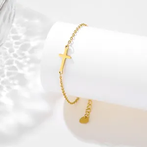 Detail of gold cross bracelet with adjustable clasp on a white textured stand