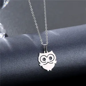 Polished stainless steel owl pendant necklace with intricate cut-out details on a display