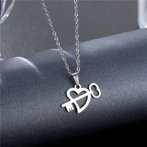 Polished silver stainless steel hollow heart key pendant necklace on grey display