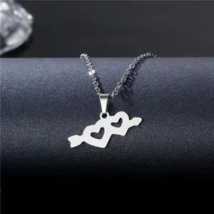 Polished silver double heart arrow necklace displayed on a minimalist grey pedestal