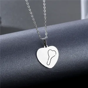 Polished stainless steel heart locket necklace with key-shaped cutout on gray background