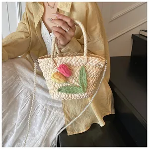 Detail of woven straw bucket bag with crochet tulip flowers and pearl chain strap
