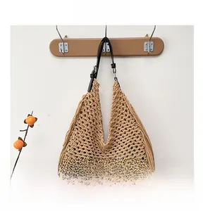 Detailed close-up of woven cotton shoulder bag with long fringe and black leather strap