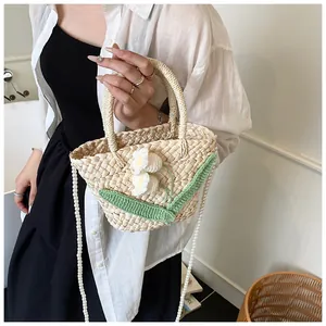 Detail of hand-woven straw bag featuring delicate crochet flowers and pearl bead strap