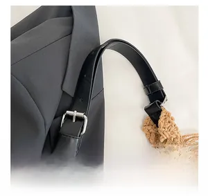 Detail of adjustable black leather strap with silver buckle on woven cotton tote bag