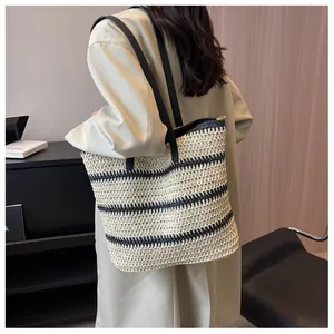 Close-up of woven tote bag showing beige and black straw texture with gold zipper