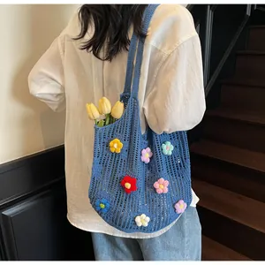 Detail view of blue crochet tote bag featuring 3D floral accents and open knit texture