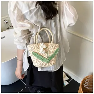 Detail of woven straw bucket bag with floral crochet patterns and a pearl chain strap