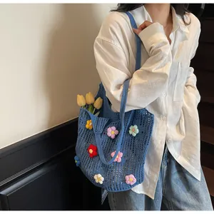 Detail of blue crochet tote bag featuring colorful handmade 3D floral appliques and mesh texture