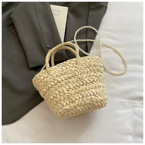 Close-up of woven straw handbag with elegant pearl strap and natural texture detail