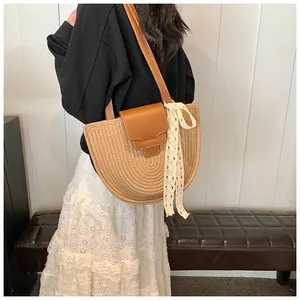 Détail du sac à bandoulière en paille tissée avec lanière en cuir et ruban de dentelle blanc