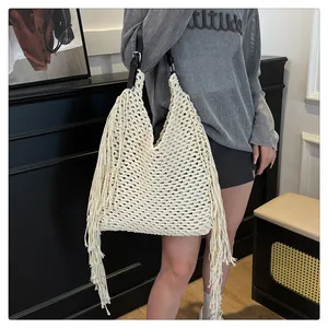 Close-up of bohemian hollow-out woven tote bag with fringe tassels and black leather strap