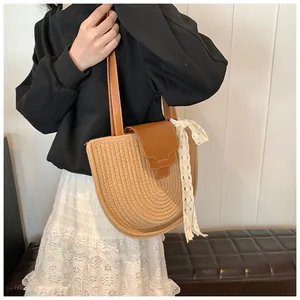 Détail d'un sac à bandoulière en paille avec rabat en cuir et foulard en dentelle
