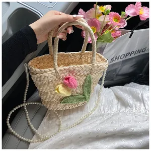 Close-up of woven straw handbag with handmade knit tulips and elegant pearl chain strap
