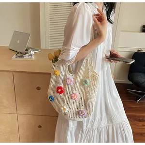 Detailed close-up of a white hand-knitted tote bag featuring vibrant 3D floral accents